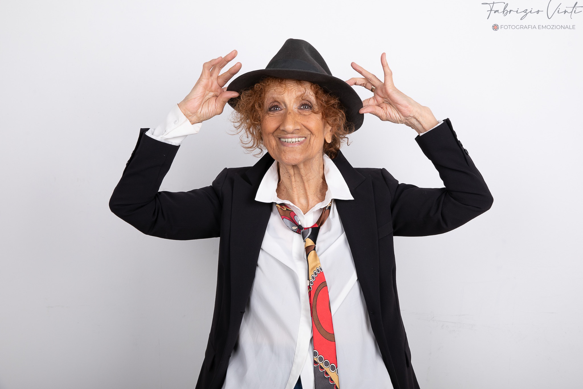 Anna Mazzamauro sorridente con cappello nero e abito scuro, fotografia di Fabrizio Vinti